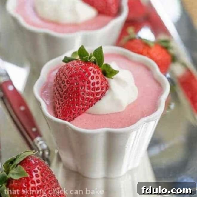 Strawberry Mousse in small white ramekins garnished with whipped cream and half a strawberry.