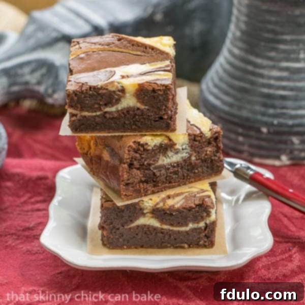 Three decadent Ricotta Cheesecake Brownies stacked on a clean white plate, showcasing the beautiful swirl.
