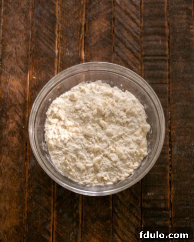Step 1: Combining flour, powdered sugar, salt, and cold butter pieces in a bowl to begin making the shortbread crust for blueberry bars.