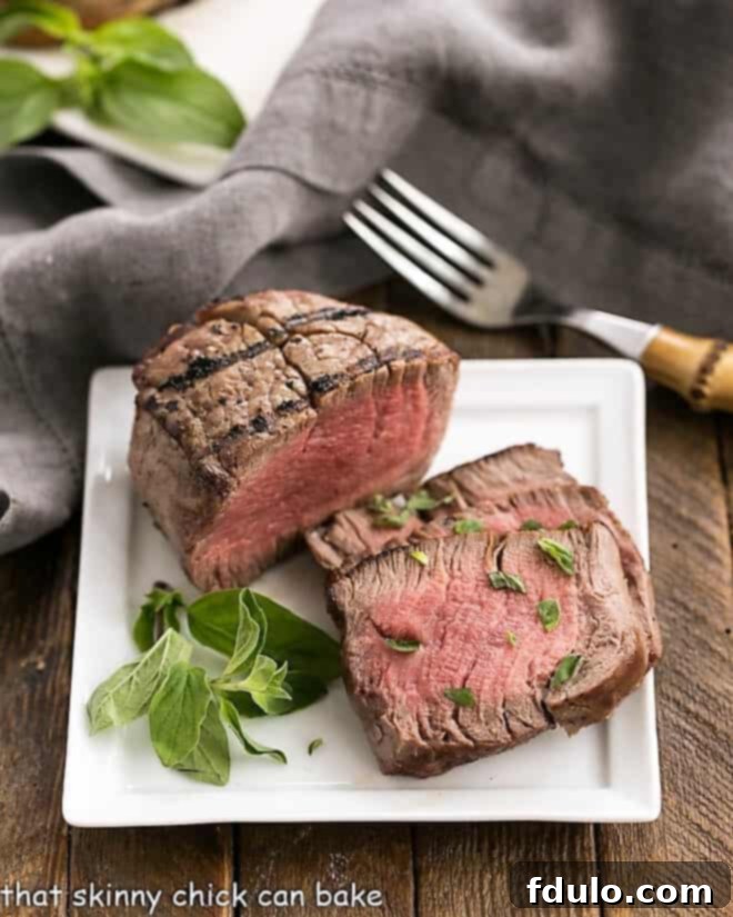 Grilled Steak with Garlic Butter on a square white plate garnished with herbs.