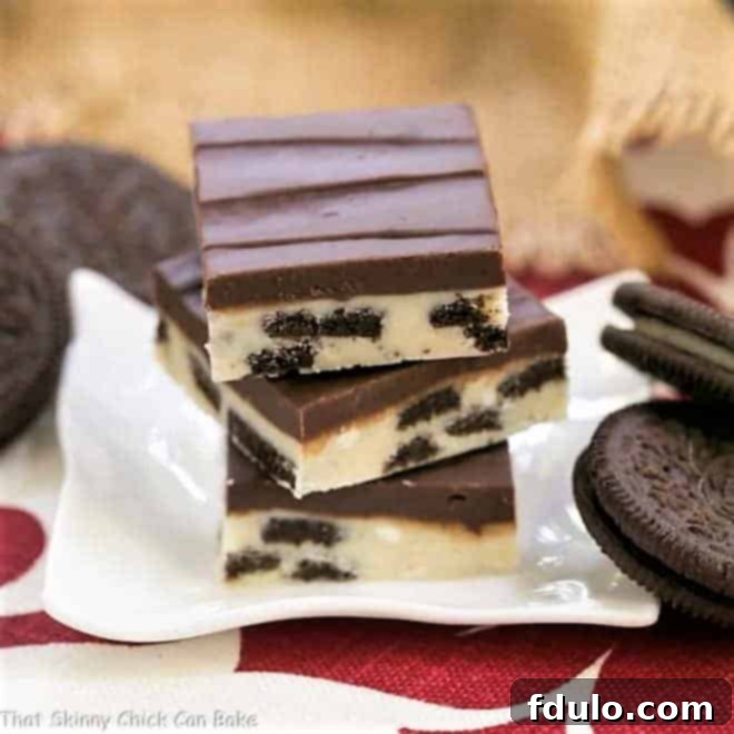 A stack of Oreo Double Decker Fudge on a white ceramic plate, showcasing its distinct layers.