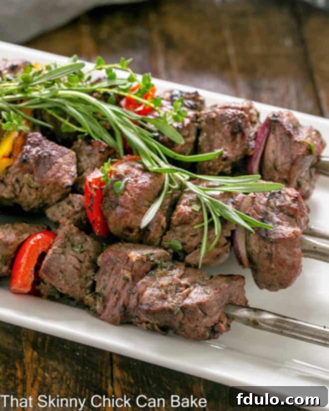 Close up of perfectly skewered lamb kebabs on a white serving tray, ready to be enjoyed.