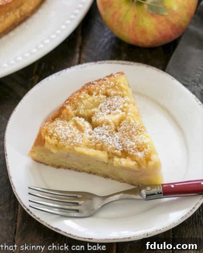 Overhead view of a slice of French apple cake with a fork, ready to be eaten.