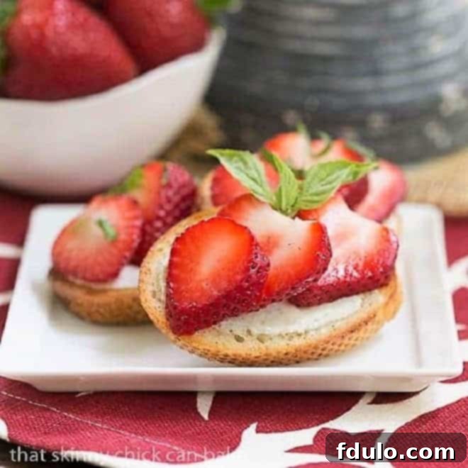Beautifully arranged Strawberry Basil Crostini on a small white appetizer plate, showcasing vibrant red strawberries and green basil