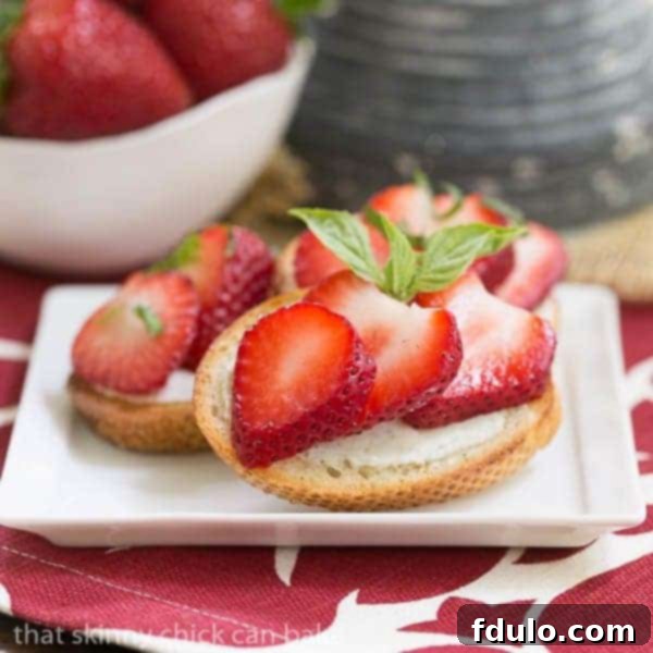 Close-up overhead shot of a finished Strawberry Basil Crostini with vibrant strawberries, basil, and balsamic drizzle
