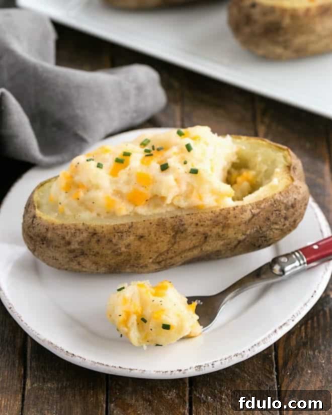 Easy Twice Baked Potatoes on a round white plate garnished with paprika and chives