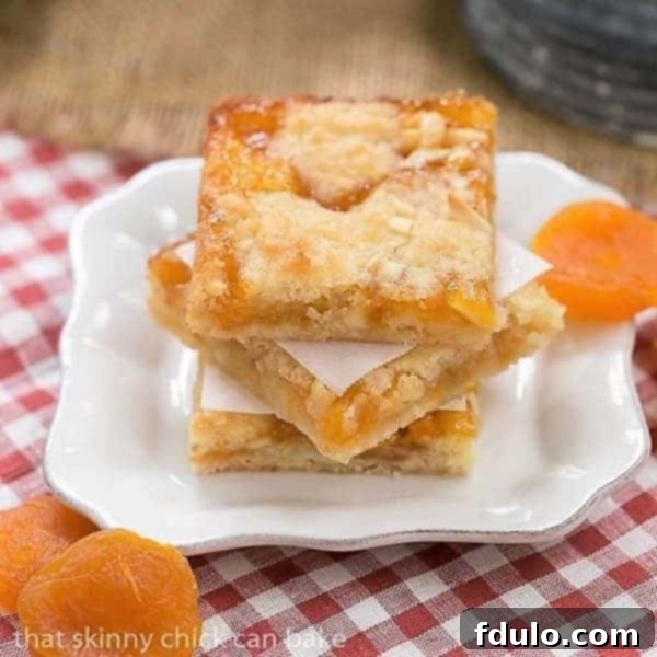 Stacked Coconut Apricot Bars on a small white plate, showcasing golden layers of cookie and jam.