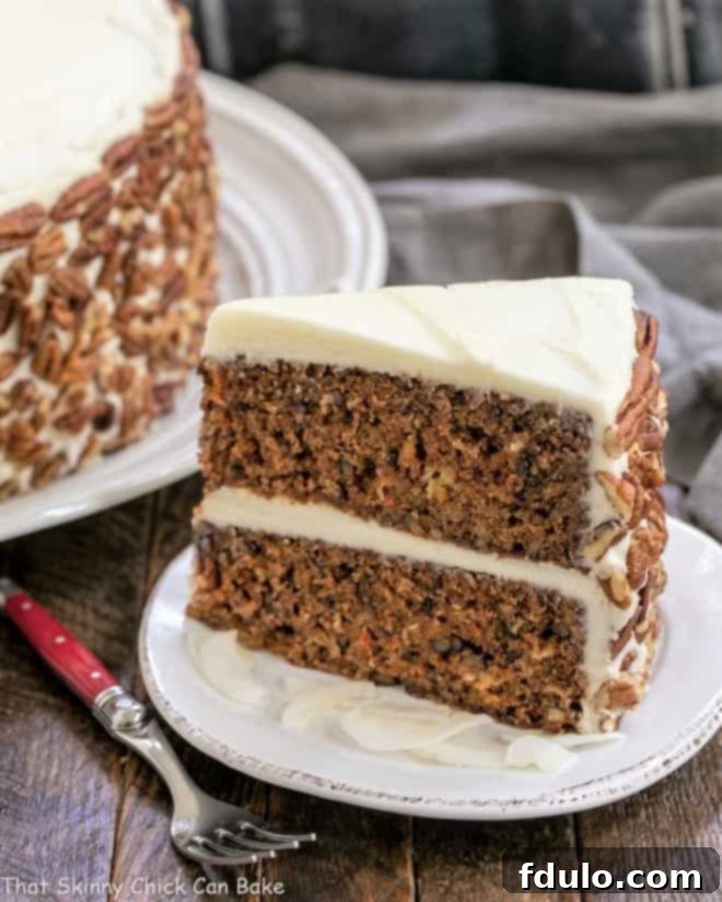 Classic Carrot Cake with Pineapple, Coconut and Pecans - Dense, delicious and loaded with flavor and texture, then topped with decadent cream cheese frosting Slice of Classic Carrot Cake on a white plate with a red handled fork, ready to be enjoyed.