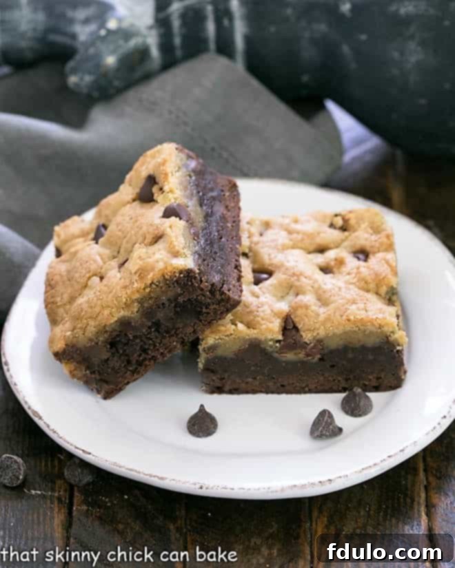 Two brookies stacked on a round white plate with a scattering of chocolate chips, emphasizing their rich texture.
