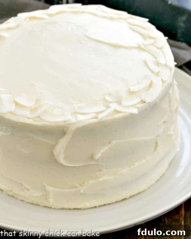 Side view of a beautifully frosted Italian Cream Cake on a white serving plate, highlighting its impressive height and layers.