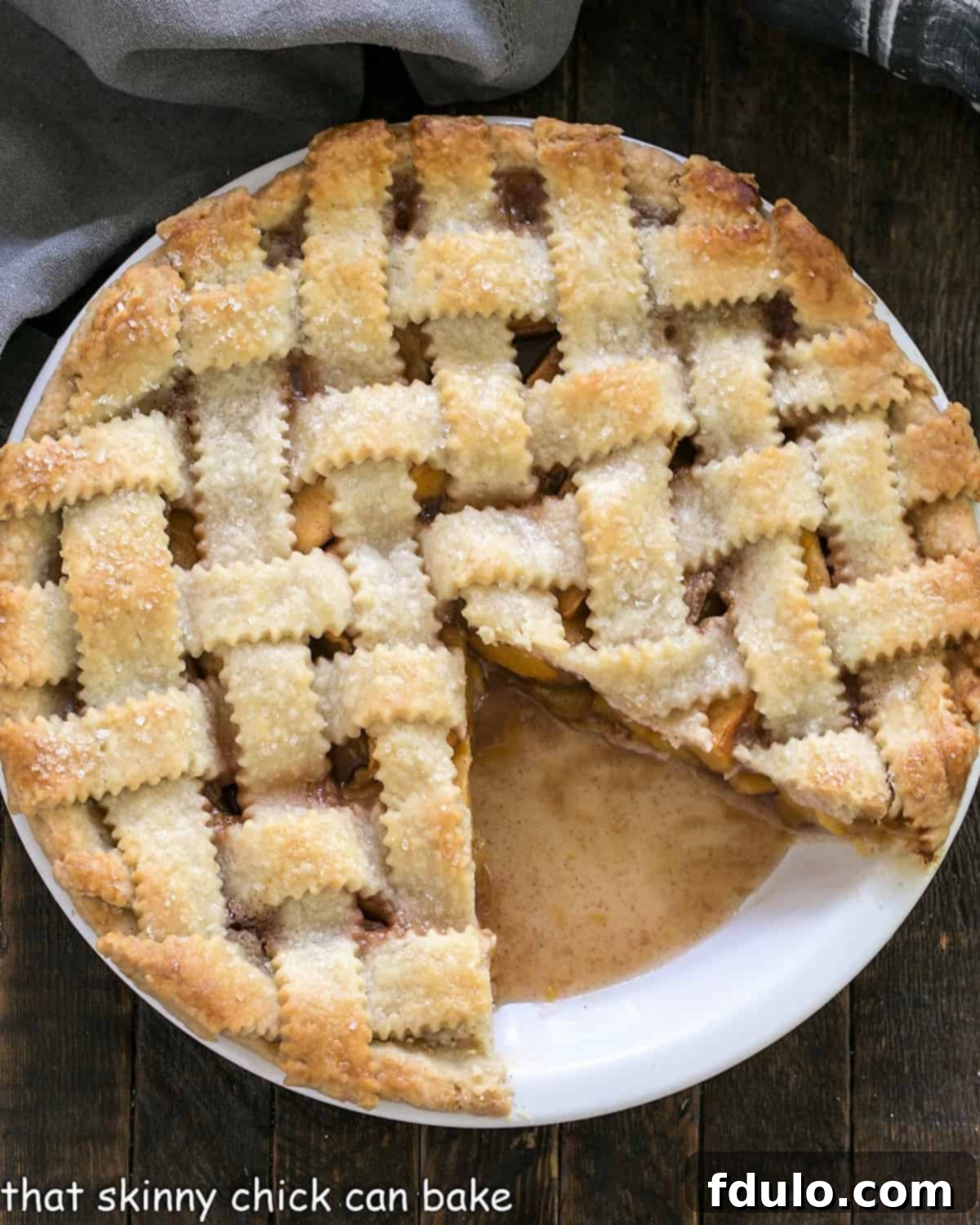Peach Pie with a lattice crust with a slice removed, revealing the sweet and juicy peach filling inside.