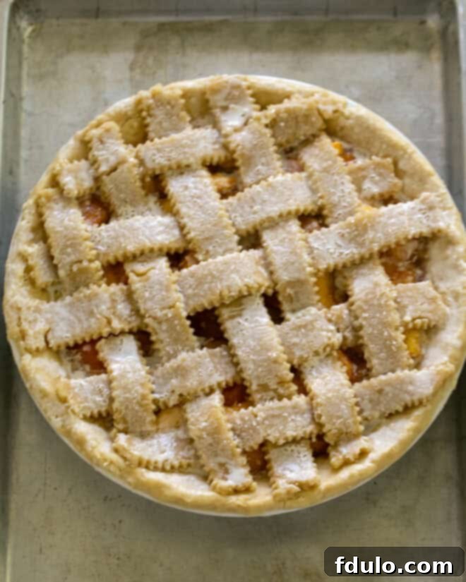 Lattice Topped Peach Pie Step 3 - Strips of pie dough are being woven over the peach filling to create a lattice pattern.