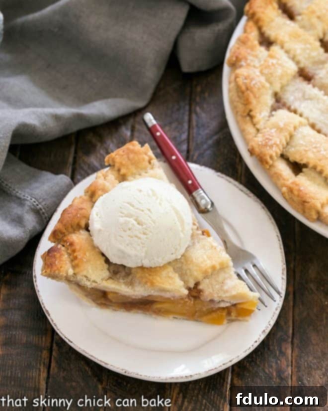 A slice of peach pie on a dessert plate with a red handled fork, ready to be enjoyed.