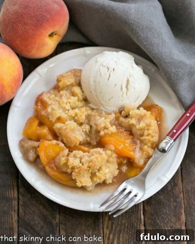 Overhead view of a Classic Peach Crisp on a white plate with a scoop of vanilla ice cream, ready to be served.