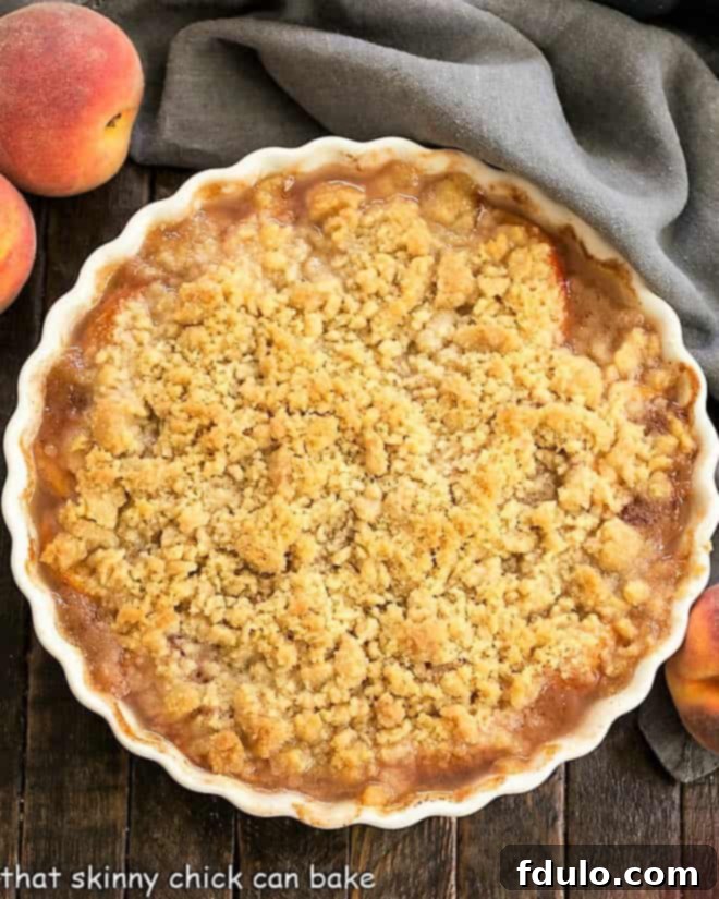 Overhead view of a Classic Peach Crisp in a white ceramic baking dish, ready to be served.