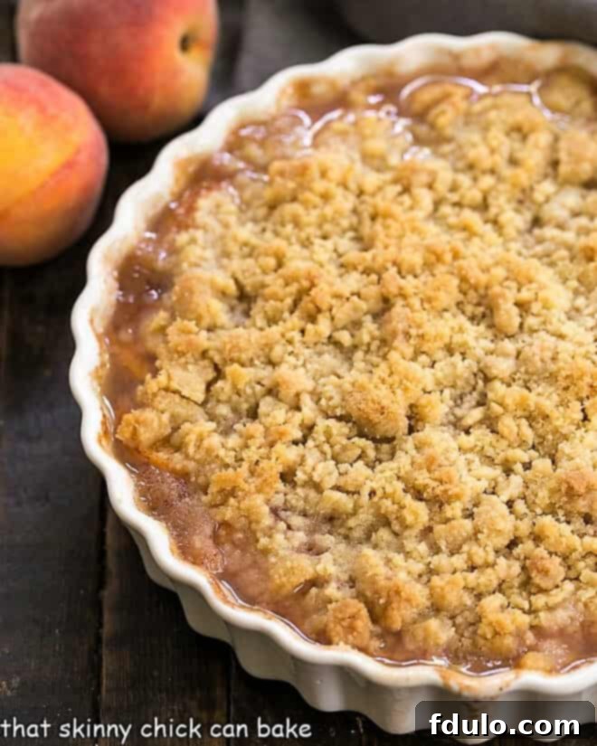 Classic Peach Crisp baked in a round scalloped casserole dish, fresh from the oven.