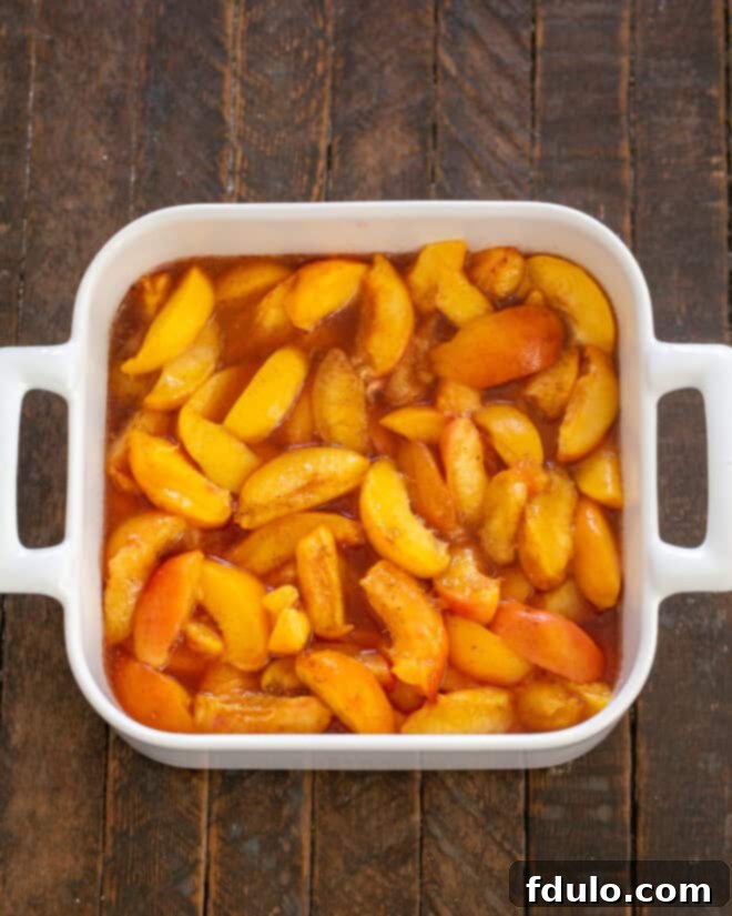 Sweetened peaches placed into a baking dish.