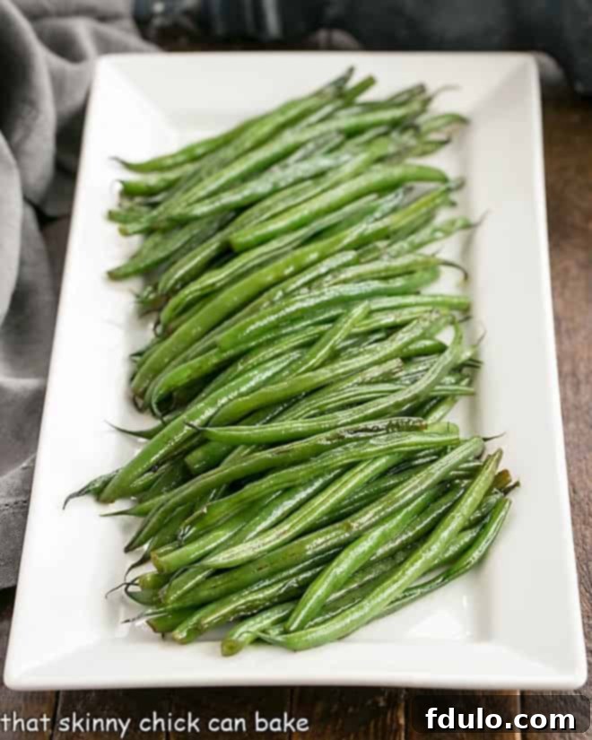 Asian Green Beans Recipe on a white ceramic platter, garnished with sesame seeds.