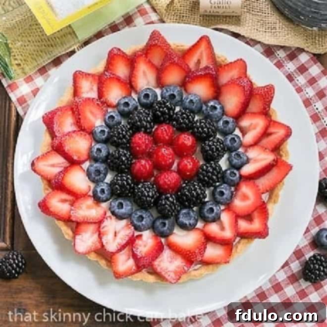 Summer Fruit Tart - Pastry crust with whipped cream and cream cheese filling topped with glorious summer berries Summer Fruit Tart on a white plate with a bottle of white wine.