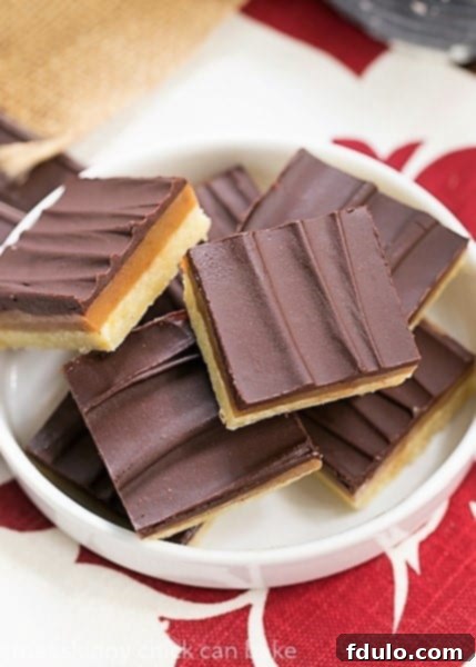 Ganache Topped Caramel Bars on a rimmed white plate, ready to be enjoyed.