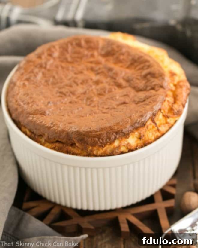 A perfectly risen French Gruyere Souffle in a white ceramic souffle dish, ready to be served.
