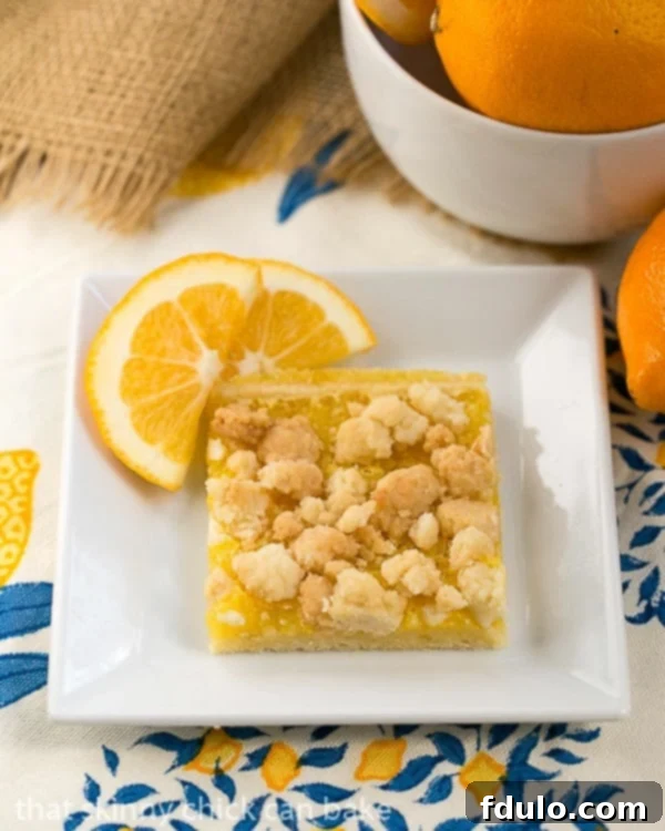 Scrumptious lemon bars with a sugar cookie crumble topping and Meyer lemon filling on a shortbread crust! Meyer Lemon Streusel Bars on a white dish garnished with lemon slices, showcasing the three distinct layers.
