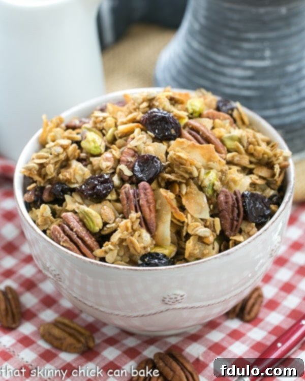 Maple Coconut Granola - An irresistible granola sweetened with maple syrup and full of nuts, seeds and dried cherries A generous serving of Maple Coconut Granola displayed in a large white bowl, resting on a charming checked napkin, highlighting its rustic appeal and delightful mix of ingredients.