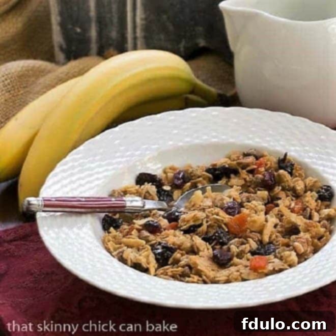 Tropical Maple Crunch Granola 2 A serving of homemade Pistachio Coconut Granola in a pristine white cereal bowl, accompanied by a red-handled spoon, highlighting its vibrant colors and inviting texture.