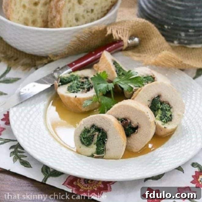 Golden-brown Chicken Saltimbocca Pinwheels with spinach and prosciutto on a white ceramic basket weave plate, garnished with fresh herbs, next to a red knife