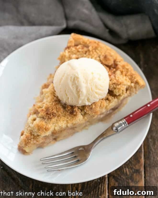Apple Crumb Pie - Cinnamon spiced apples in a pastry shell with a streusel topping Dutch Apple Pie slice on a white plate with a red handled fork.
