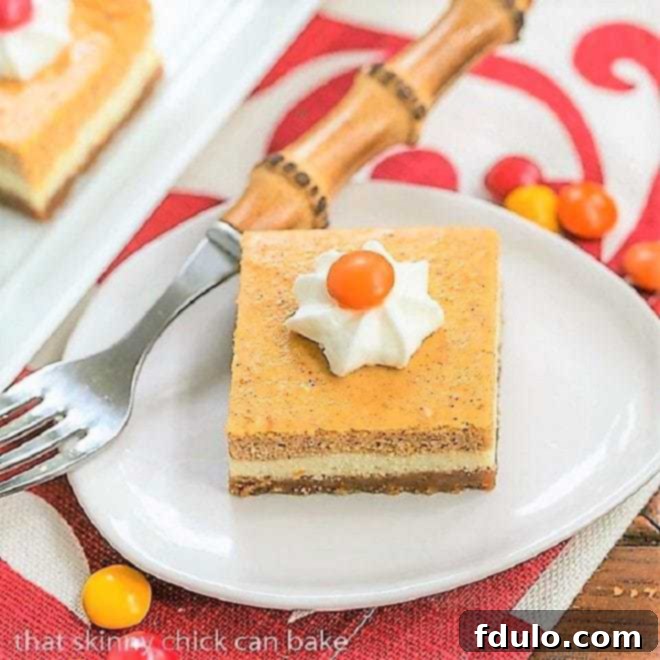 Pumpkin Cheesecake Bars on a small white plate, showing the distinct layers of crust, plain cheesecake, and pumpkin cheesecake