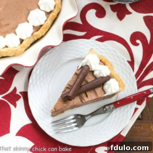 Classic French Silk Pie - A sublime, dreamy chocolate creation A slice of Classic French Silk Pie on a plate with a red handled fork.