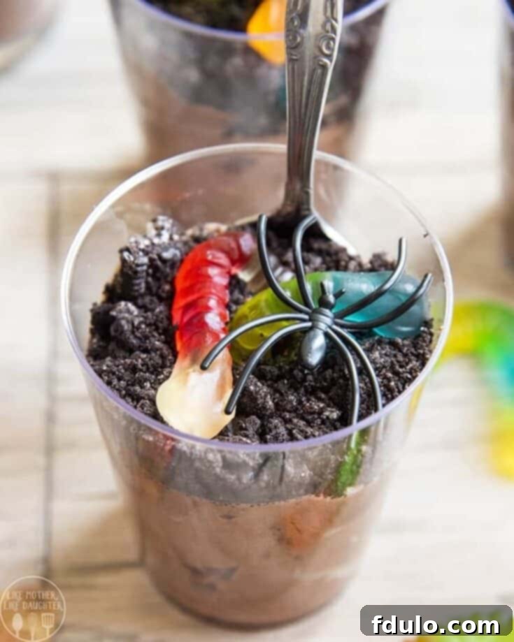 Creepy Crawly Pudding Cups, a spooky take on the classic dirt dessert, complete with gummy worms and crushed cookies.