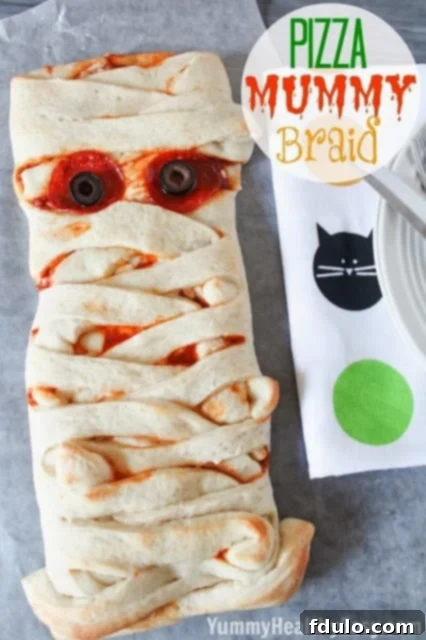 A creative Pizza Mummy Braid, shaped like a mummy and filled with delicious pizza toppings, perfect for a Halloween dinner.