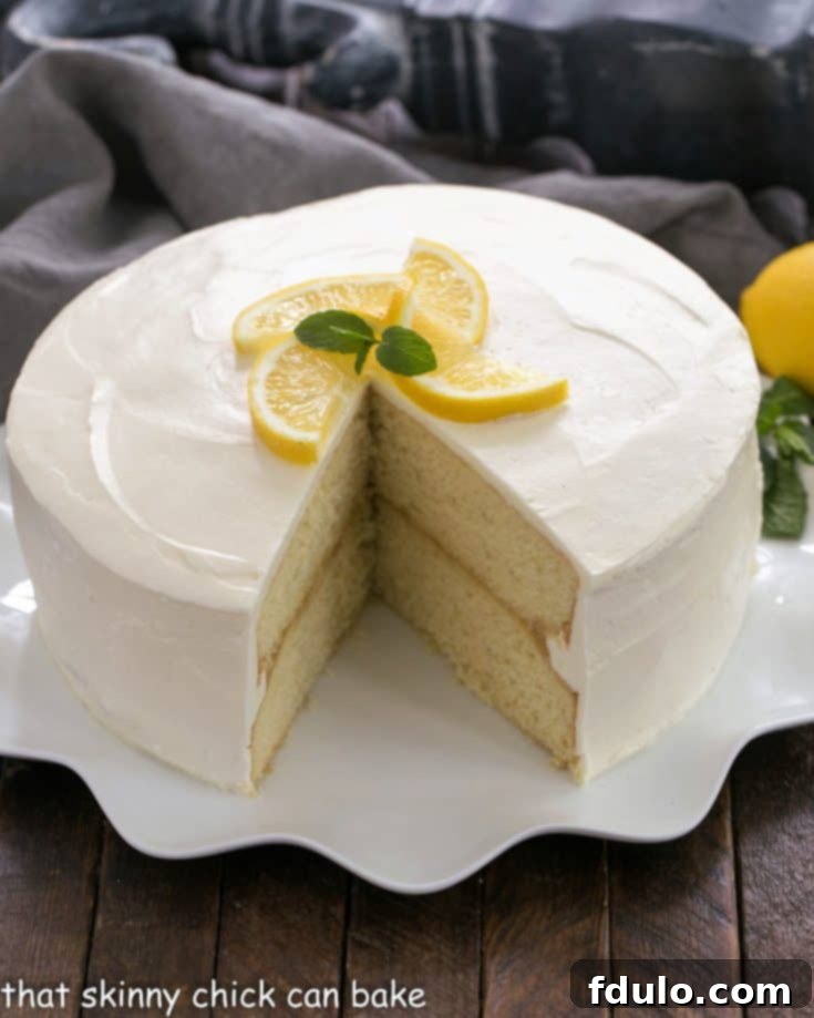 Lemon Cake with lemon curd filling on a white cake plate with a slice removed