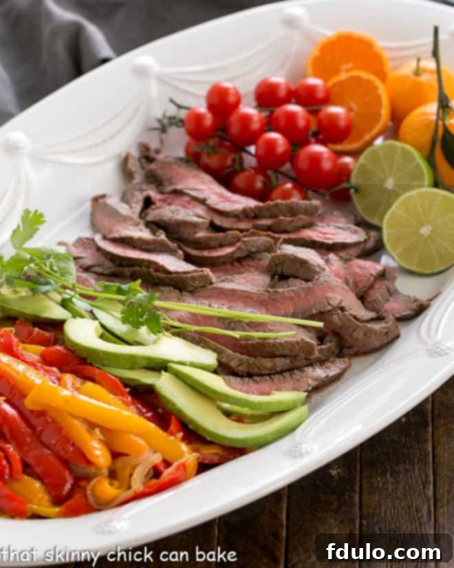 Easy Beef Fajitas - Marinated and grilled beef flank steadk wrapped in a tortilla for an easy weeknight supper Flank Steak Fajitas and toppings on a white platter.