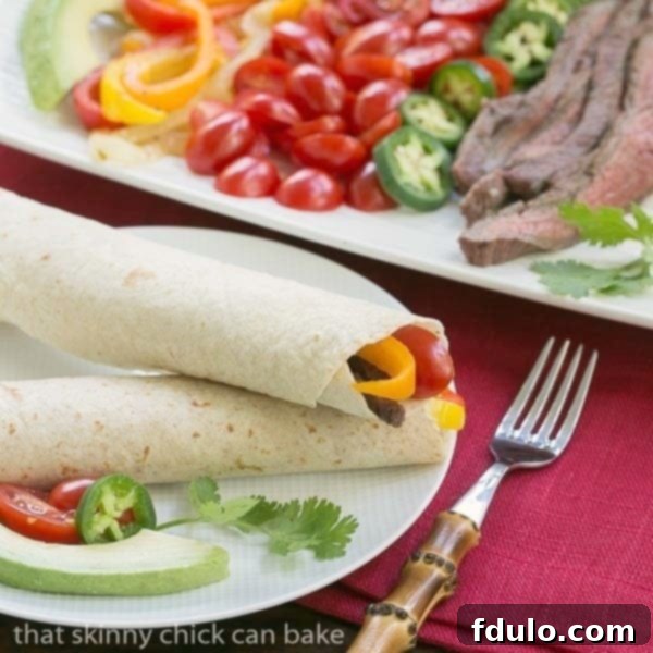 Two Flank Steak Fajitas neatly wrapped and arranged on a white dinner plate.
