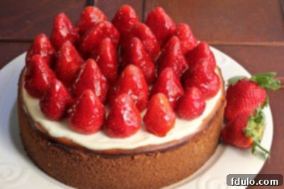 A rich and creamy Strawberry Topped Cheesecake topped with luscious ripe strawberries! strawberry topped cheesecake on a white plate