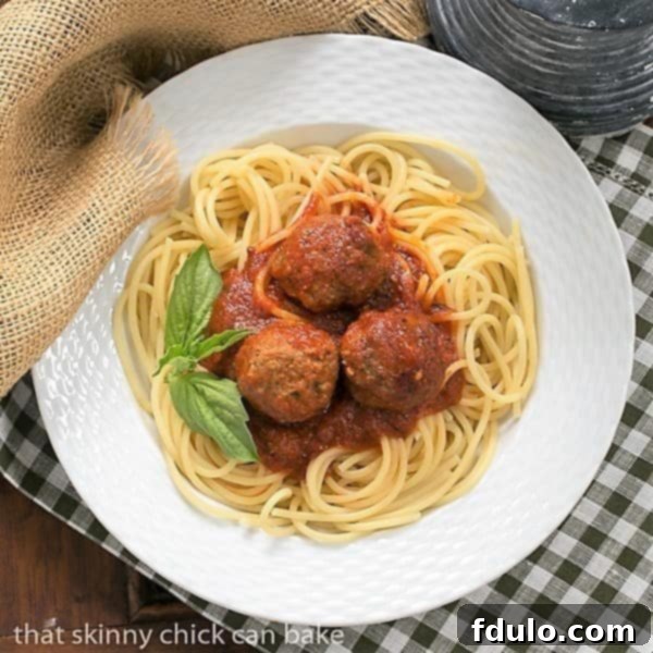 An overhead shot showcasing Classic Italian Meat Sauce served over spaghetti, accompanied by perfectly formed meatballs, all in a large white bowl.