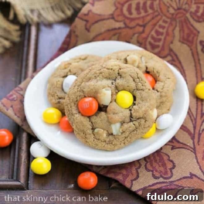Three M&M White Chocolate Macadamia Nut Cookies elegantly arranged on a small white plate, showcasing their delightful texture and colorful candies.