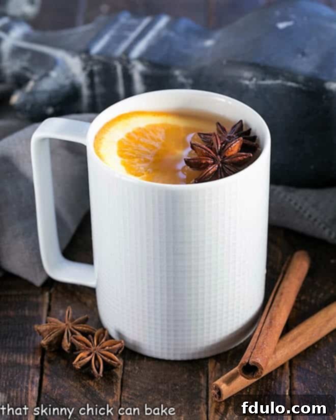 Spiced Apple Cider Warmth 2 Hot apple cider in a white mug a slice of orange to garnish