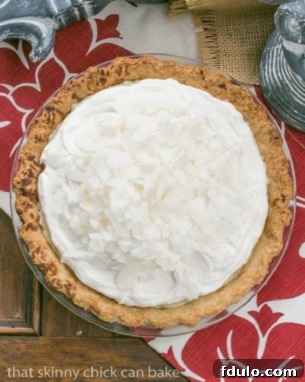 Indulgent Slice of Coconut Cream Pie - Pure Dessert Perfection Close-up of a slice of Coconut Cream Pie, showing the layers of coconut crust, creamy custard, and fluffy whipped cream topping, garnished with toasted coconut.