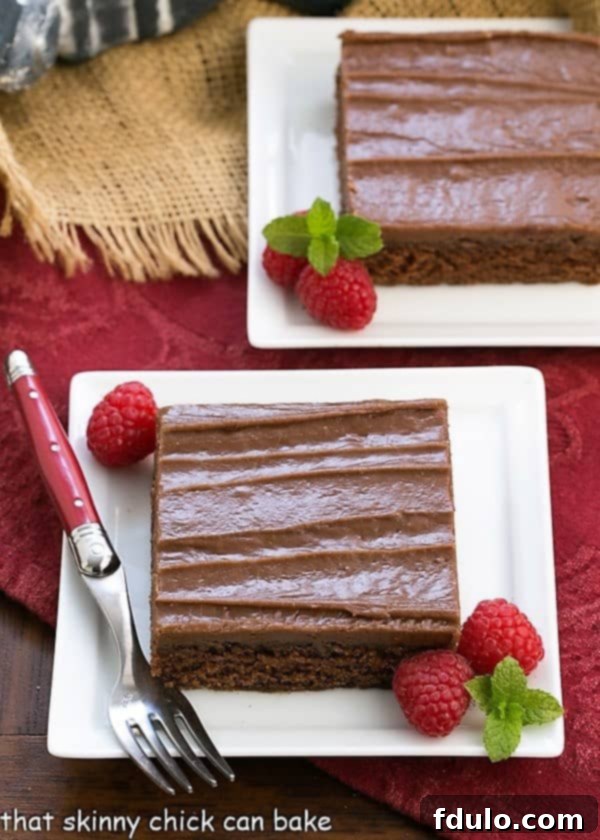 Multiple slices of rich, fudgy Chocolate Sheet Cake, each adorned with fresh raspberries, arranged on various square white plates, showcasing a delectable dessert perfect for sharing.