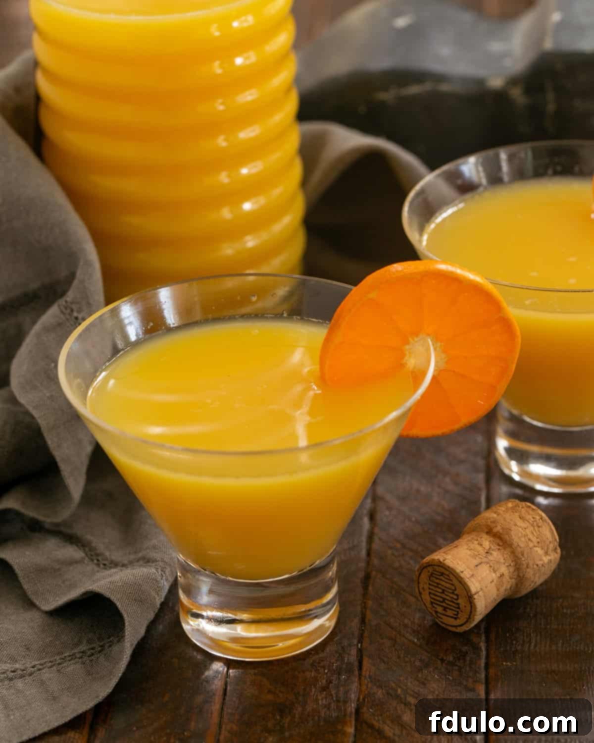 Grand Marnier Mimosas - The classic orange juice and champagne cocktail with the optional splash of Grand Marnier Grand Mimosas in Viski Glasses in front of a pitcher of mimosas.