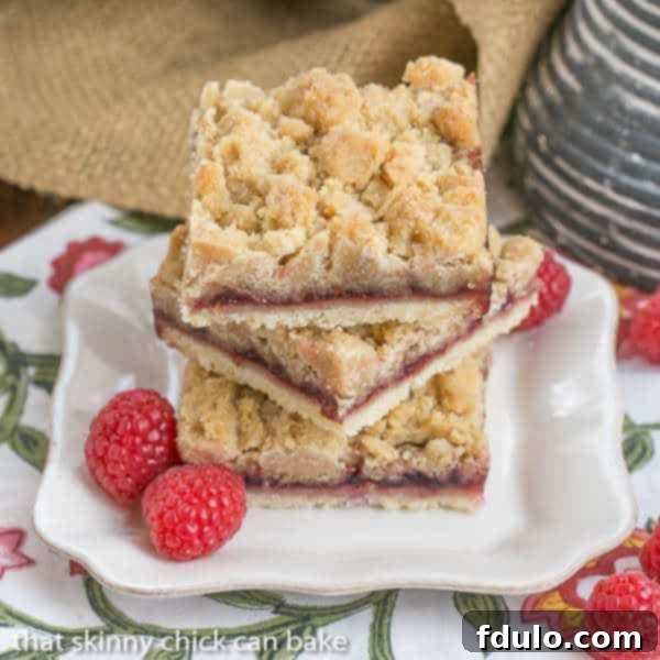 A stack of golden-baked Raspberry Crumb Bars with a visible jam layer and crumb topping, presented invitingly.