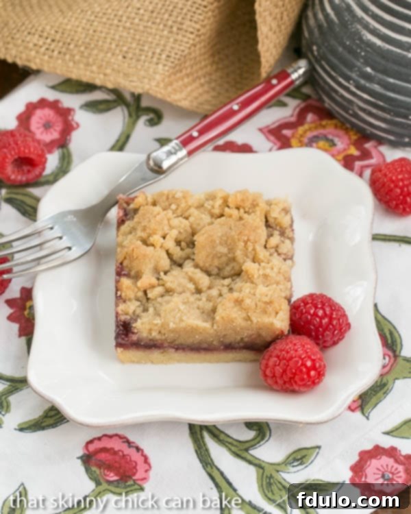 Close-up of a Raspberry Crumb Bar, showcasing the textured streusel topping and the vibrant red jam filling.