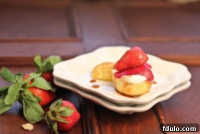 Cream puff filled with whipped cream and topped with fresh berries, ready to be served on a stack of plates
