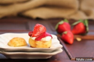 A close up of a single cream puff filled with whipped cream and topped with fresh berries, showcasing the delicious filling