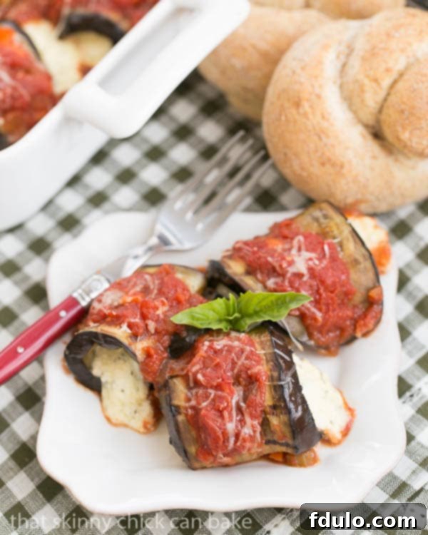 Eggplant Rollatini - A delightful vegetarian entree featuring grilled eggplant rolled around a ricotta mozzarella filling Eggplant Rollatini with Ricotta and Mozzarella on a square white plate garnished with fresh basil