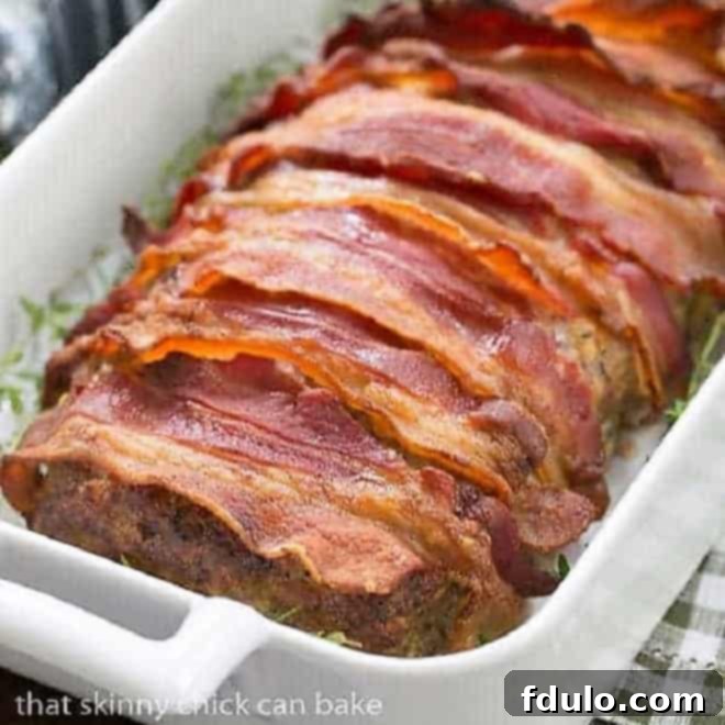 Bacon Wrapped Meatloaf in a white casserole dish garnished with fresh thyme.